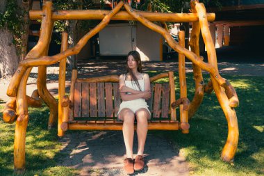 Genç bir kadın, dışarıda, kırsal bir salıncakta dalgın dalgın oturuyor. Waterton, AB