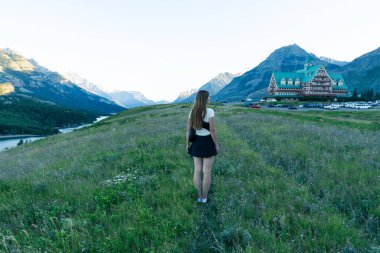 Bir kadın görkemli dağlarla çevrili bir dağ kulübesinin manzarasından hoşlanır. Waterton, AB