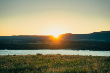 Altın saat manzarayı ılık ışıkta yıkıyor, göl gökyüzünün renklerini yansıtıyor. Waterton, AB