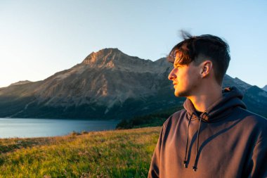 İnsanoğlu, sıcak bir günbatımı parıltısıyla aydınlanan uzak dağa bakar. Waterton, AB