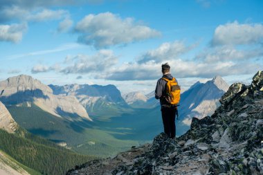 Yürüyüşçü kayalık tepeden sırt çantasıyla dağ manzarasını izliyor. Çadır Sırtı, Kananaskis, AB