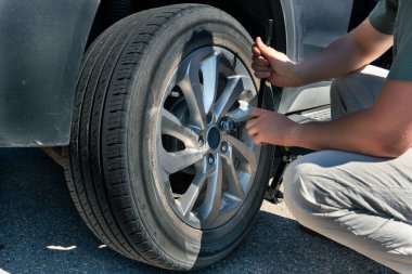 Bijon anahtarıyla arabanın lastiğini değiştiren birine yakın çekim. Banff, AB