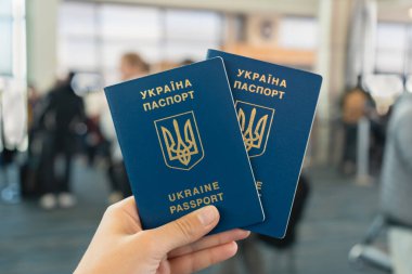 Yoğun havaalanında elinde altın amblemi olan bir çift pasaport. Ukrayna pasaportu