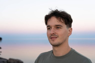 Genç adam, alacakaranlık saatlerinde sakin okyanus sularını düşünüyor. Burlington, ON