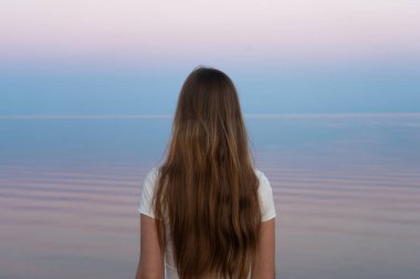 Kız ufka doğru bakıyor, dalgalı saçları özgürlük hissini yansıtıyor. Burlington, ON