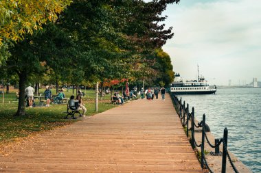 İnsanlar deniz kenarındaki sakin parkın tadını çıkarıyorlar, ahşap geçidin yanındaki. Toronto, ON