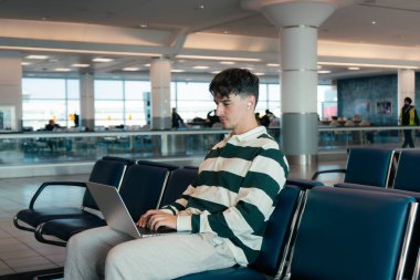 Bilgisayarlı genç adam havaalanında uçağını bekliyor. Toronto, ON