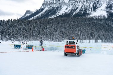 Karlı bir tarlada buz şatosu, arka planda dağlar ve ormanlar inşa ediliyor. Kış teması. Etkinlik terfisi ve mevsimlik kampanyalar için uygun. En fazla 150 charmax