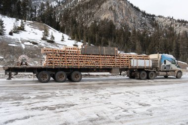 Bir kamyon karlı yolda ağır yük taşıyor. Sahne gösterisi endüstrisi, taşımacılık, ulaşım ve lojistik, güzel dağ zeminine karşı hazırlanıyor.