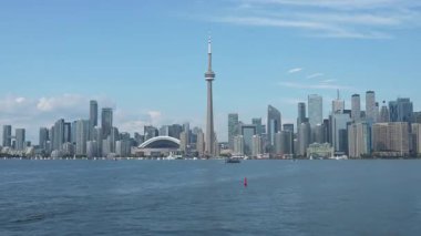 Hareketli bir şehrin panoramik manzarası. Yüksek binalar ve sakin sular üzerinde göze çarpan bir kule.