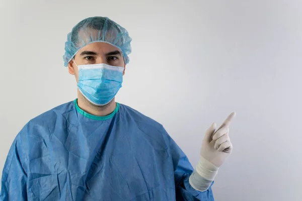 Ana konu bulanık, genç erkek cerrah beyaz arka plan üniformalı doktor sağlık hizmetleri beyaz tıbbi eldivenler acil durum noktasını gösteriyor.