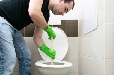 Common Household drenaj problemleri, semptomlar tıkanma tıkanma, tuvalet tıkanıklığı tıkanma açıcı güç bardağı erkek adam mutsuz bir şekilde yerde oturuyor.
