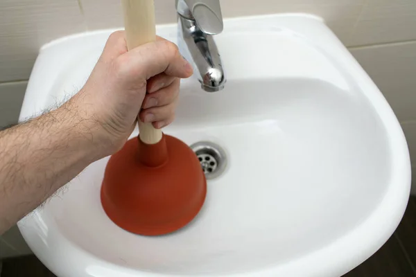 The main subject is out of focus, Solving Common Household Drain Problems, symptoms Solutions blockage plumbing bathroom sink unclog plunger force cup male man hand hold