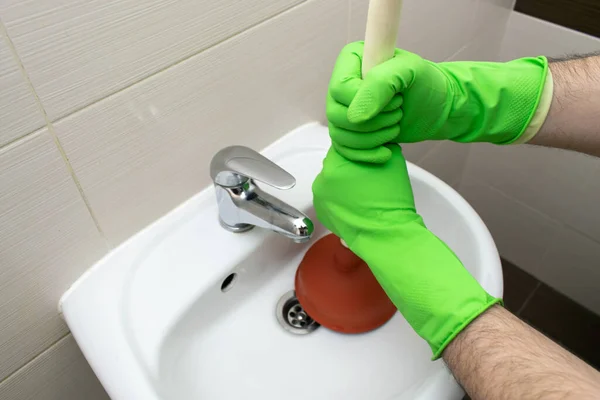 The main subject is out of focus, Solving Common Household Drain Problems, symptoms Solutions blockage plumbing bathroom sink unclog plunger force cup male man hand hold