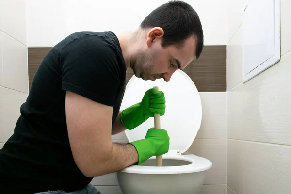 Common Household drenaj problemleri, semptomlar tıkanma tıkanma, tuvalet tıkanıklığı tıkanma açıcı güç bardağı erkek adam mutsuz bir şekilde yerde oturuyor.