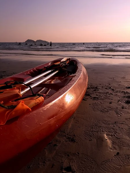 Красный каяк с веслом и спасательным жилетом — стоковое фото