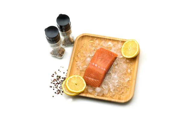 一片新鲜的鲑鱼 冰柠檬在白色背景的木制正方形盘子里 盐和香料 高质量的照片 — 图库照片