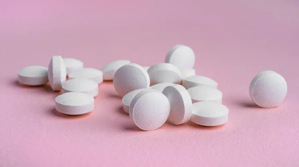 Vita tabletter på rosa bakgrund. — Stockfoto