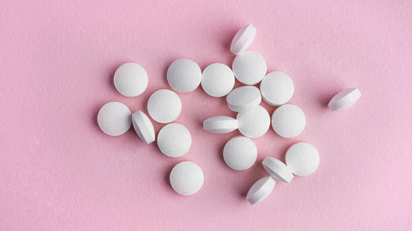 Vita tabletter på rosa bakgrund. — Stockfoto