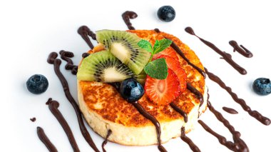 Beyaz arka planda çikolatalı ve meyveli cheesecake..