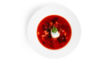 Kırmızı, sıcak pancar çorbası, ekşi krema ve beyaz arka planda izole edilmiş otlar..