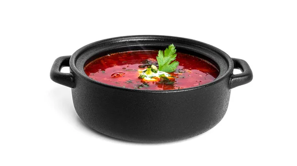 Merah, panas borscht sup bit dengan krim asam dan herbal dalam pot hitam terisolasi pada latar belakang putih. — Stok Foto