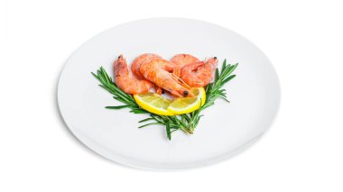 Beyaz arka planda izole edilmiş siyah bir tabakta limonlu ve biberiyeli haşlanmış karides..