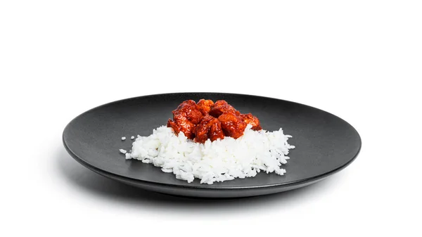 Свинина тушкована з рисом на чорній тарілці ізольована на білому тлі. Гуляш з рисом. Рис з м'ясом . — стокове фото