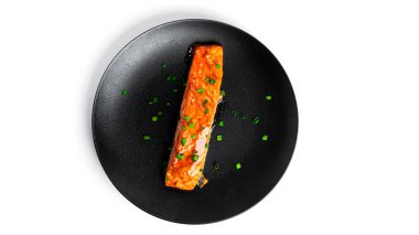 Soya soslu fırınlanmış somon balığı ve siyah tabakta beyaz arka planda izole edilmiş otlar..