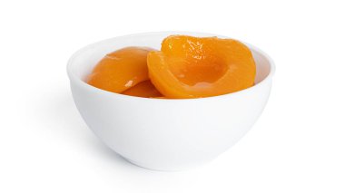 Beyaz kasede konserve şeftali. Beyaz arka planda izole edilmiş şerbetli tatlı şeftaliler..