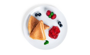 Böğürtlen reçelli krepler beyaz arka planda izole edilmiş. Beyaz tabakta çilekli krep ve yaban mersini..