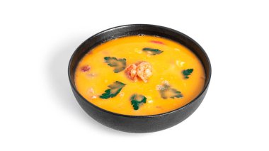 Beyaz arka planda izole edilmiş siyah bir tabakta karidesli çorba. Deniz mahsullü Tayland çorbası. Thai tom yum çorbası