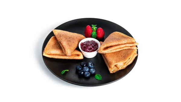 Pancakes with berry jam isolated on a white background. Pancakes with strawberries and blueberries on black plate.