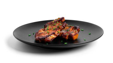 Siyah tabakta kızarmış domuz bifteği. Beyaz arka planda izole edilmiş..