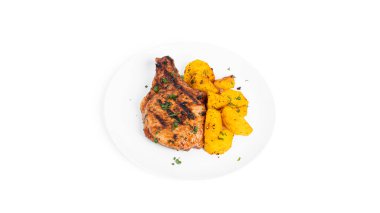 Soslu domuz bifteği ve beyaz arka planda izole edilmiş tabakta fırında patates..