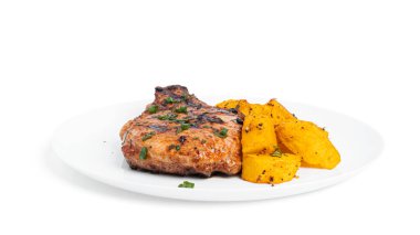 Soslu domuz bifteği ve beyaz arka planda izole edilmiş tabakta fırında patates..