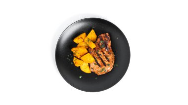 Soslu domuz bifteği ve beyaz arka planda izole edilmiş tabakta fırında patates..