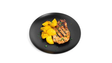 Soslu domuz bifteği ve beyaz arka planda izole edilmiş tabakta fırında patates..