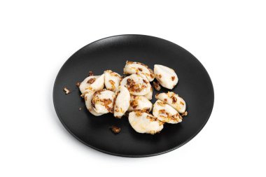 Beyaz arka planda izole edilmiş siyah tabakta patates ve kızarmış soğanlı hamur tatlısı..