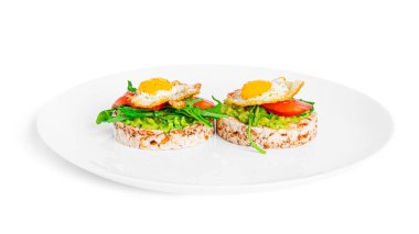 Crispbread sandwich with guacamole, arugula, tomatoes and quail egg isolated on a white background. Bruschetta with avocado. Healthy breakfast.