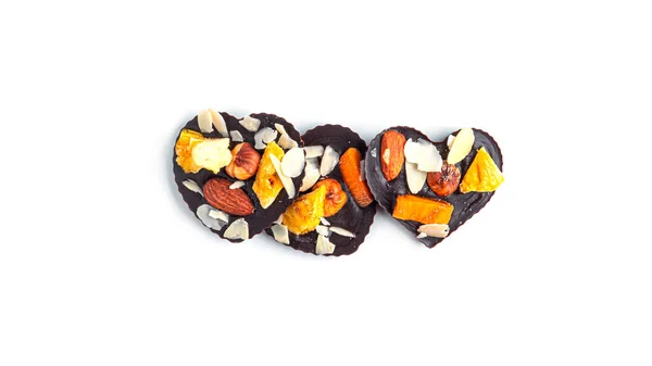 Rohe herzförmige Schokolade mit getrockneten Früchten und Nüssen auf weißem Hintergrund. — Stockfoto