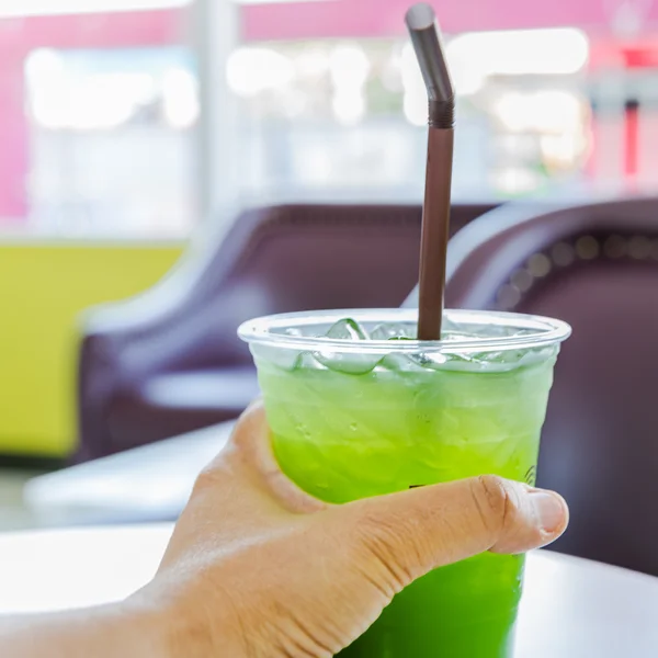 Mão segurando um copo de plástico de suco de kiwi — Fotografia de Stock