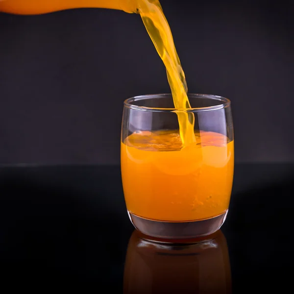 Jus d'orange mûr verser la bouteille dans un verre — Photo