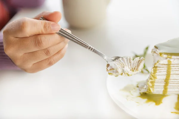 Hand taking green tea crepe cake piece