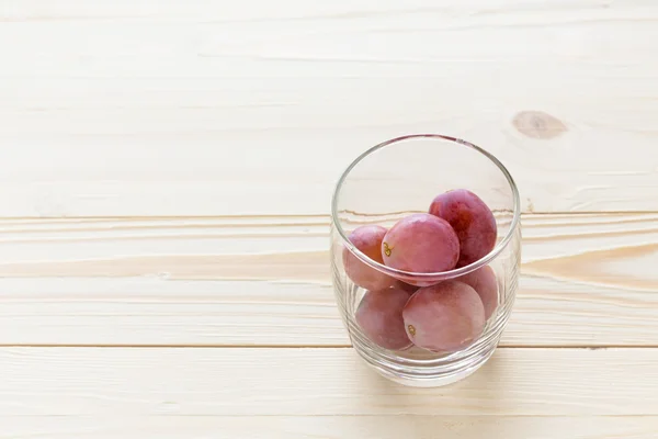 Uvas em um copo em uma mesa de madeira — Fotografia de Stock