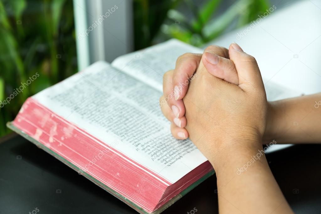 praying hand and book on desk showing religion concept