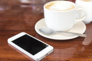 Smartphone ve ahşap arka plan üzerinde kahve