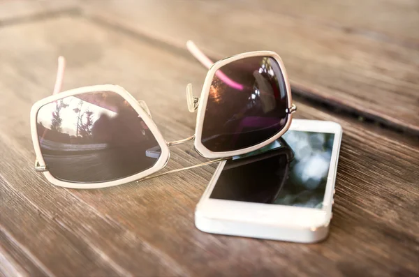 Smartphone and sunglasses on wooden table — Stock Photo, Image
