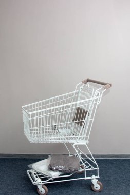 Mini alışveriş arabası, boş, duvarın karşısında duruyor..