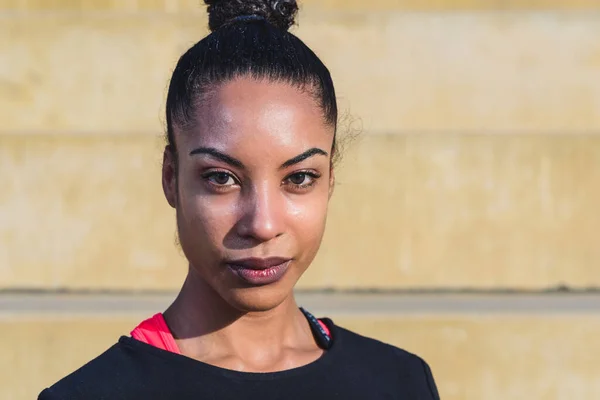 Çekici, at kuyruklu, spor giyinmiş ve kameraya bakan Afro-Amerikan bir modelin açık havada çekilmiş portresi. Boşluğu sağda kopyala